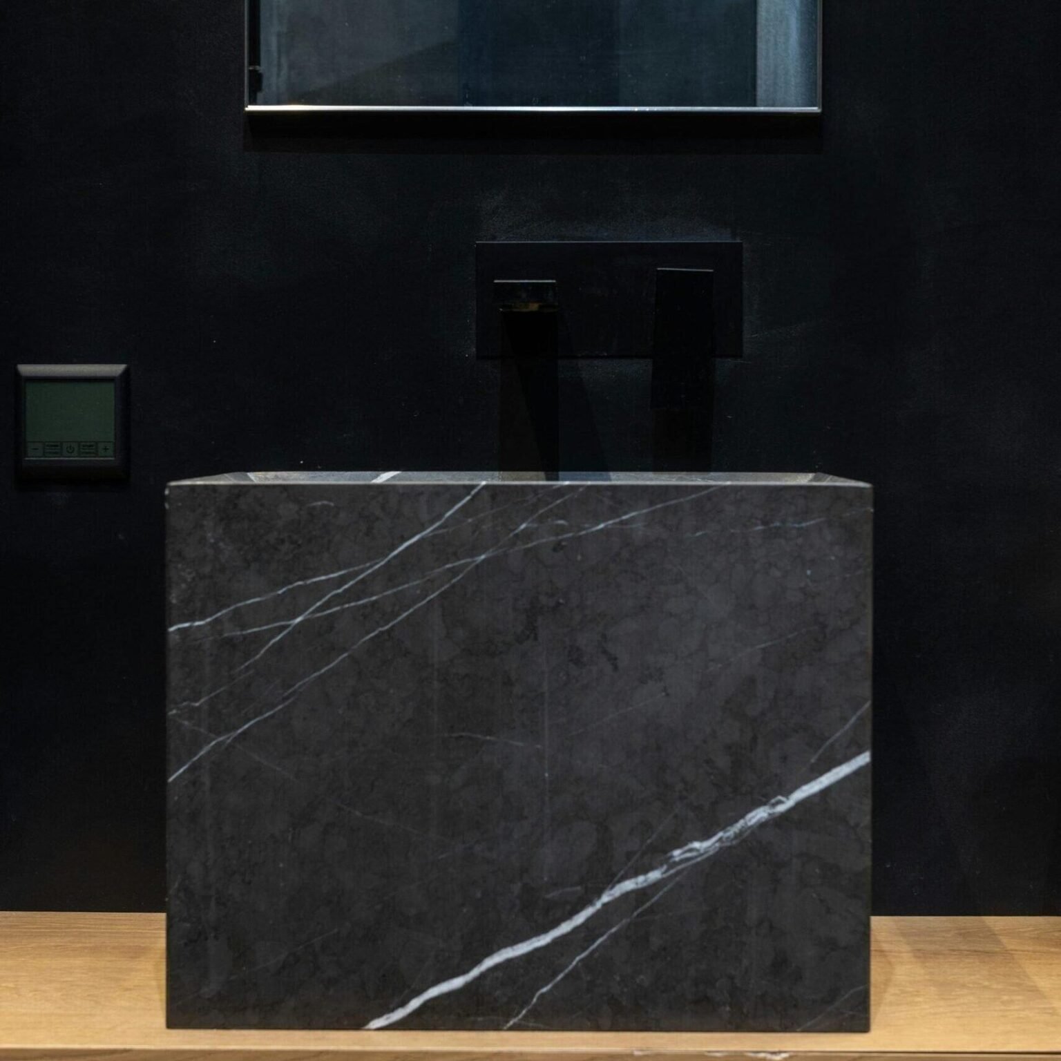 Lavabo de bloque de mármol negro con vetas blancas y grifería negra mural