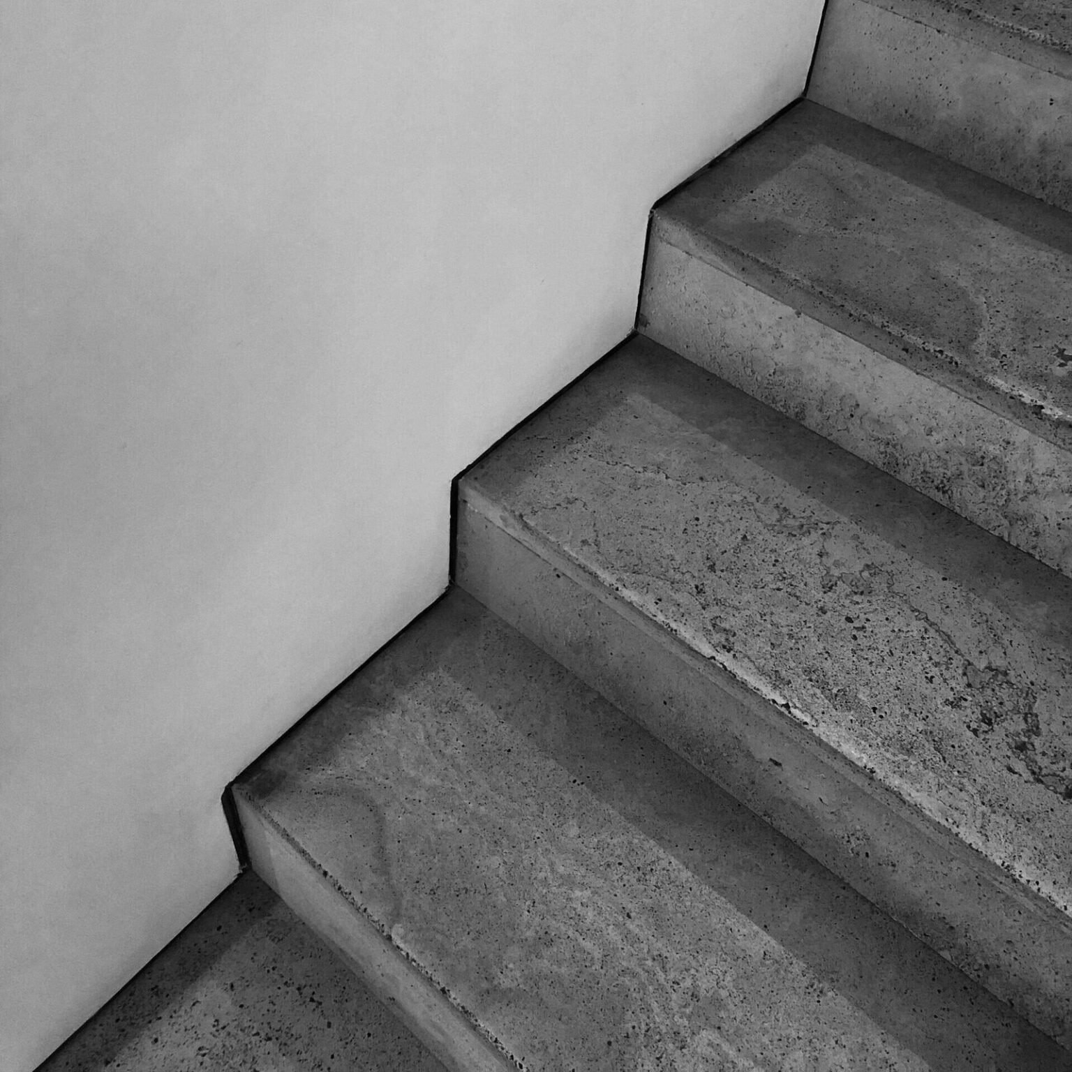 Peldaños de piedra gris en una escalera junto a una pared clara