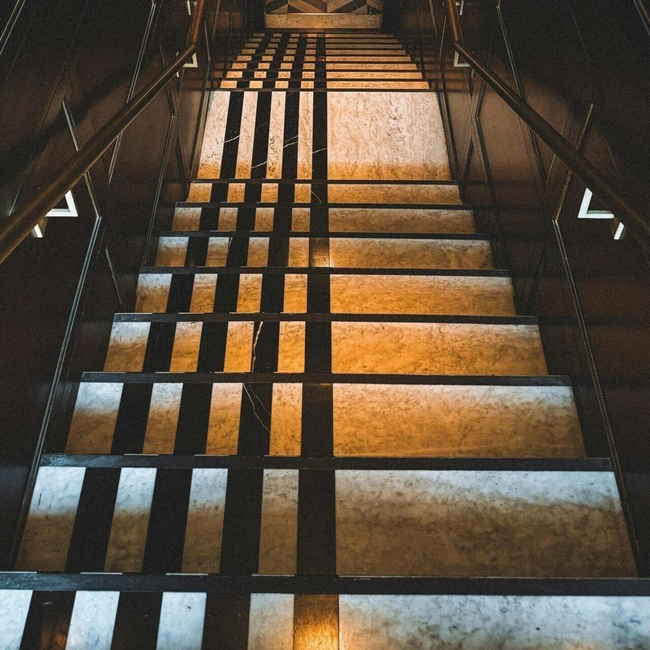 Escalera con peldaños de piedra retroiluminados y barandilla negra
